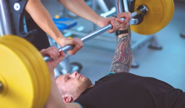 Genç adam eğitmen ile spor salonunda halter kaldırma