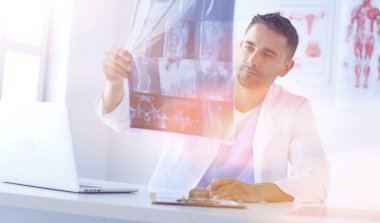 Yakışıklı doktor genç bayan hastasıyla konuşuyor ve ofisinde otururken notlar alıyor..