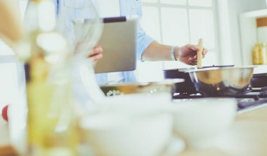 Dijital tablet ve yemek pişirme tarifine uyan bir adam evdeki mutfakta lezzetli ve sağlıklı yemekler pişiriyor.