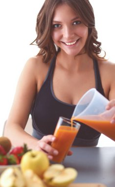 Mutfakta masada meyve suyu ve bardakla oturan bir kız.