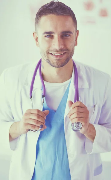 Retrato médico masculino joven y confiado de pie en el consultorio médico. — Foto de Stock