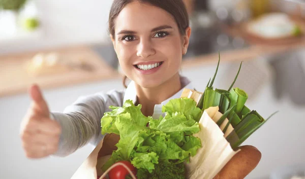 Mujer joven sosteniendo bolsa de la compra de comestibles con verduras y mostrando ok —  Fotos de Stock