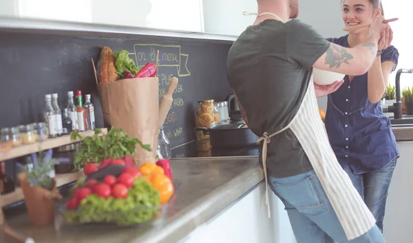 Bir çift evdeki mutfaklarında birlikte yemek pişiriyor.