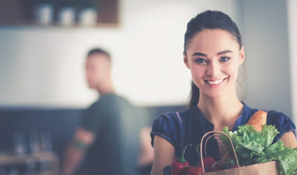 Jong stel in de keuken, vrouw met een zak boodschappen doen — Stockfoto