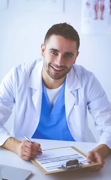 医務室の机に座ってノートパソコンを持つ男性医師の肖像画 — ストック写真