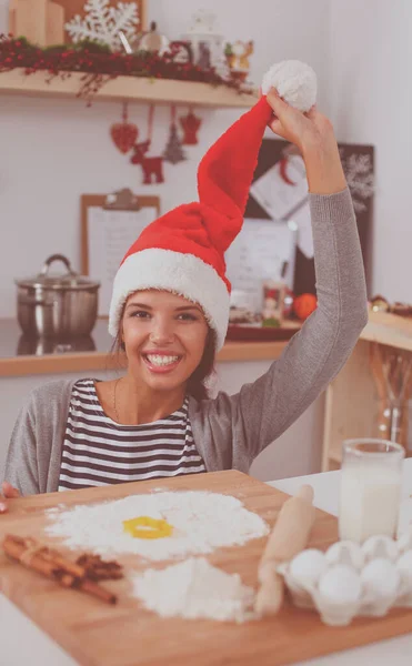 Woman in santa hat making christmas cookies in the kitchen — Stock Photo, Image