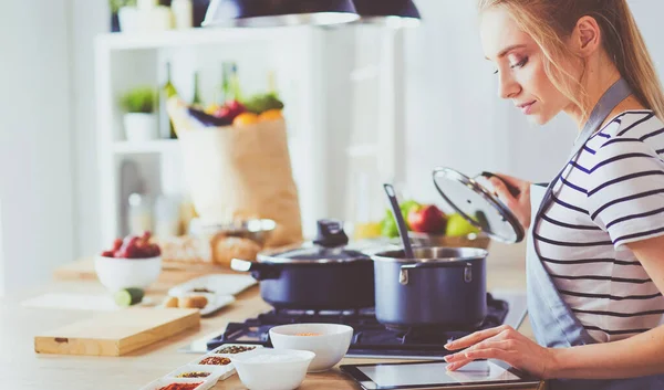 Mujer joven usando una tableta para cocinar en su cocina — Foto de Stock