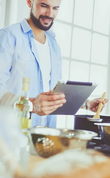 Hombre siguiendo la receta en la tableta digital y cocinar comida sabrosa y saludable en la cocina en casa — Foto de Stock