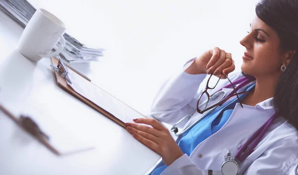 Ärztin sitzt mit Papier auf dem Schreibtisch und arbeitet — Stockfoto