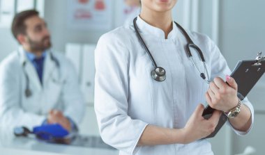 Kadın doktor hastanede steteskopla dikiliyor.