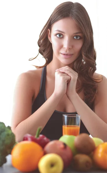 Flicka sitter i köket på skrivbord med frukt och glas med juice — Stockfoto