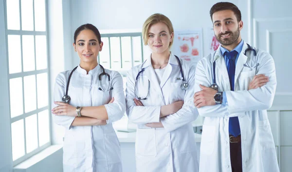 Успешная команда врачей смотрит в камеру и улыбается стоя в больнице — стоковое фото