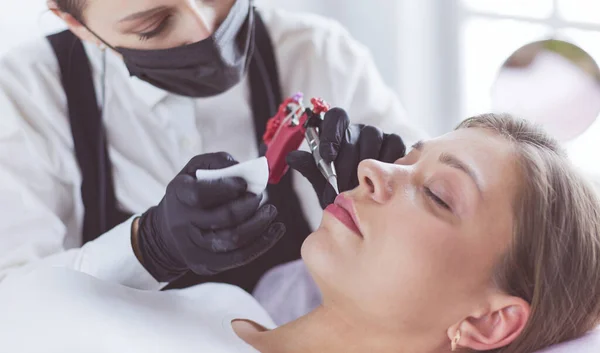 Cosmetólogo aplicando maquillaje permanente en las cejas —  Fotos de Stock