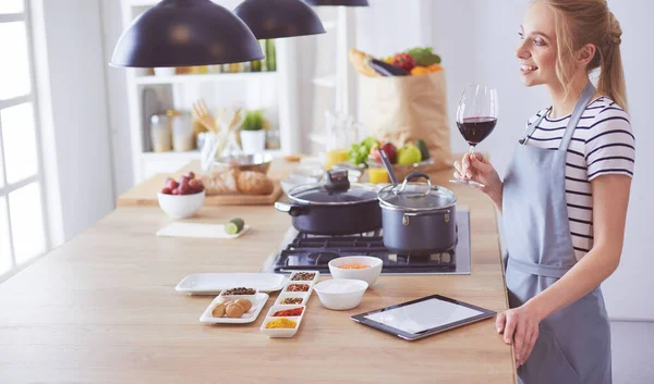 Mulher bonita bebendo um pouco de vinho em casa na cozinha — Fotografia de Stock