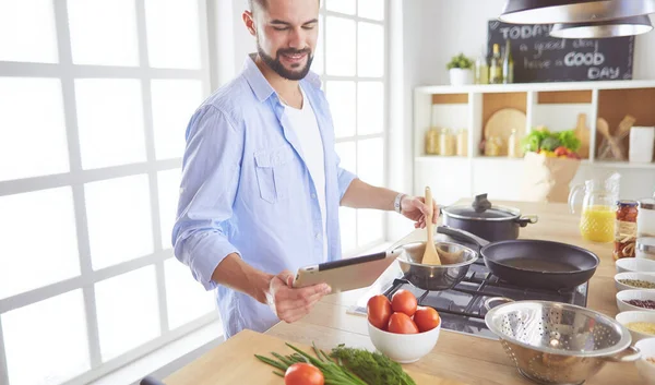 Manusia mengikuti resep pada tablet digital dan memasak makanan lezat dan sehat di dapur di rumah — Stok Foto