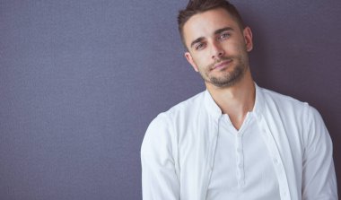 Gri arka planda yalnız oturan genç iş adamı.