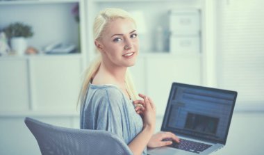 Genç ve güzel bir kadın evde dizüstü bilgisayar kullanıyor.