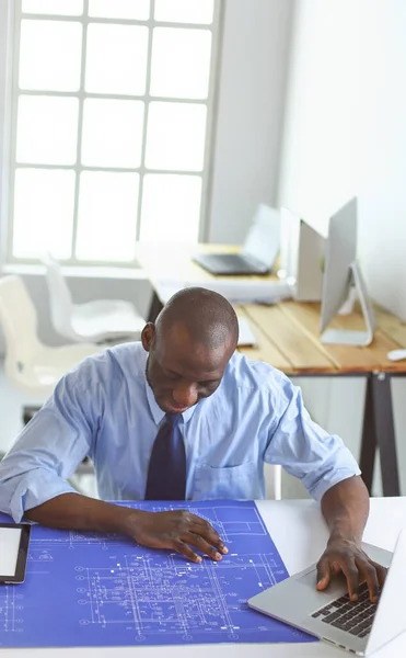 Arquitecto afroamericano trabajando con computadoras y planos en la oficina —  Fotos de Stock