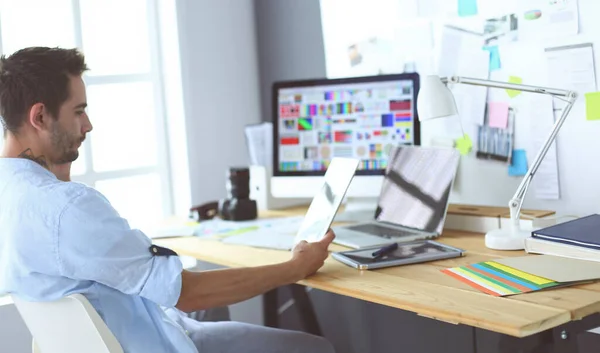 Porträt eines jungen Designers, der im Grafikstudio vor Laptop und Computer sitzt, während er online arbeitet. — Stockfoto