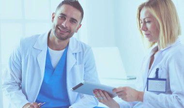 Yakışıklı doktor genç bayan doktorla konuşuyor ve ofisinde otururken notlar alıyor..