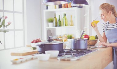 Çekici kadın mutfakta dikilirken elinde bir bardak portakal suyu tutuyor.