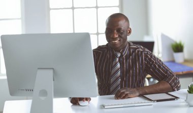 Yakışıklı Afro Amerikalı işadamı Klasik takım elbiseli bir dizüstü bilgisayar kullanarak ve ofiste çalışırken gülümseyen