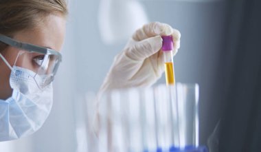 Laboratuvarda sıvı yeşil çözeltiye bakan bir tıbbi veya bilimsel araştırmacı ya da doktor.