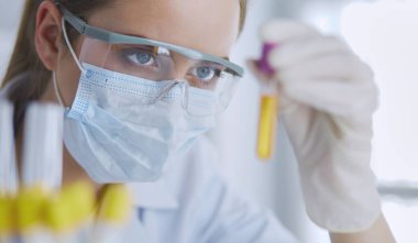 Modern laboratuvar veya hastanede plastik tıbbi tüplerle çalışan araştırmacı, doktor, bilim adamı veya laboratuvar asistanı.