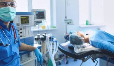 Ameliyat odasında arka planda erkek cerrah var..