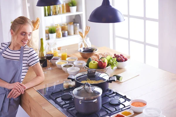 Young woman standing near desk in the kitchen .