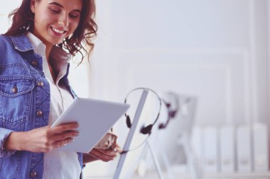 Gülümseyen kadın kahve içiyor ve kafede tablet kullanıyor.
