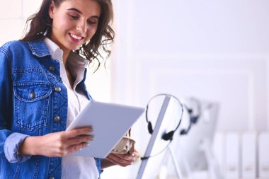 Gülümseyen kadın kahve içiyor ve kafede tablet kullanıyor.