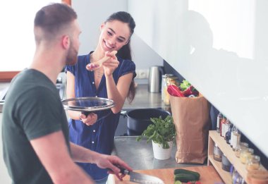 Bir çift evdeki mutfaklarında birlikte yemek pişiriyor..