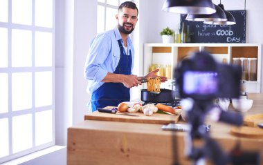 Mutfak arka planında poşet dolusu erzak tutan adam. Alışveriş ve sağlıklı gıda konsepti.