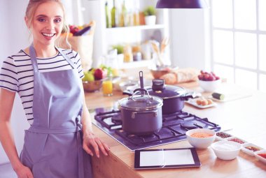 Evdeki mutfakta yemek pişiren güzel genç bir kadın..