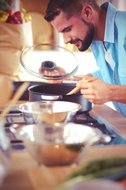 Dijital tablet ve yemek pişirme tarifine uyan bir adam evdeki mutfakta lezzetli ve sağlıklı yemekler pişiriyor..