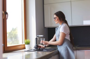 Su bardağını dolduran kadın elleri.