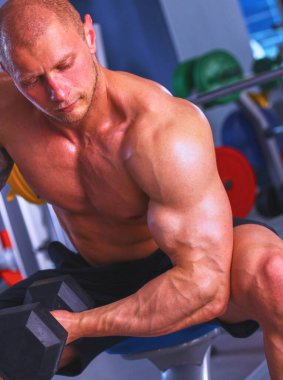 Güçlü bir adam, bir spor salonunda dumbbells ile egzersiz vücut geliştirmeci .