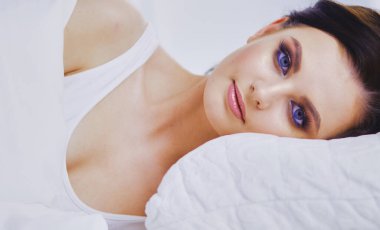 Genç ve güzel bir kadın yatakta yatıyor.