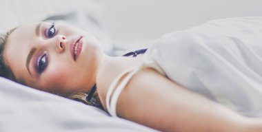 Genç ve güzel bir kadın yatakta yatıyor.