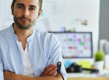 Dizüstü bilgisayar ve bilgisayar çalışırken önünde genç tasarımcı portresi. Onun mobil arka plan kullanarak Yardımcısı