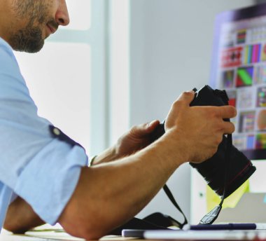 İnternette çalışırken bilgisayarın ve dizüstü bilgisayarın önünde grafik stüdyosunda oturan genç tasarımcının portresi