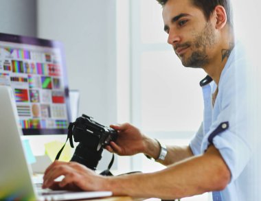 İnternette çalışırken bilgisayarın ve dizüstü bilgisayarın önünde grafik stüdyosunda oturan genç tasarımcının portresi