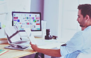 İnternette çalışırken bilgisayarın ve dizüstü bilgisayarın önünde grafik stüdyosunda oturan genç tasarımcının portresi