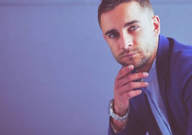 Gri arka planda yalnız oturan genç iş adamı