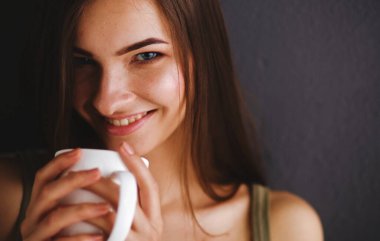 Kanepede oturan ve odada çay içme genç kadın.