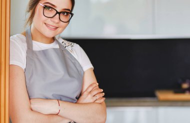 Mutfakta masanın yanında duran genç bir kadın. .