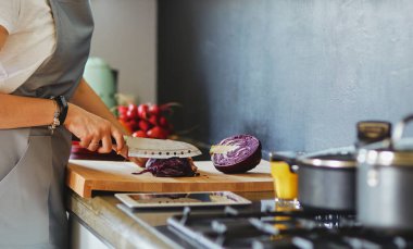Yeni mutfakta yemek pişiren kadın sebzelerle sağlıklı yemekler yapıyor..