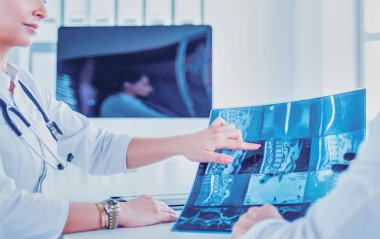 İki doktor röntgen görüntülerini inceliyor, parlak ofiste danışmanlık yapıyorlar..