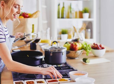 Evdeki mutfakta yemek pişiren güzel genç bir kadın..